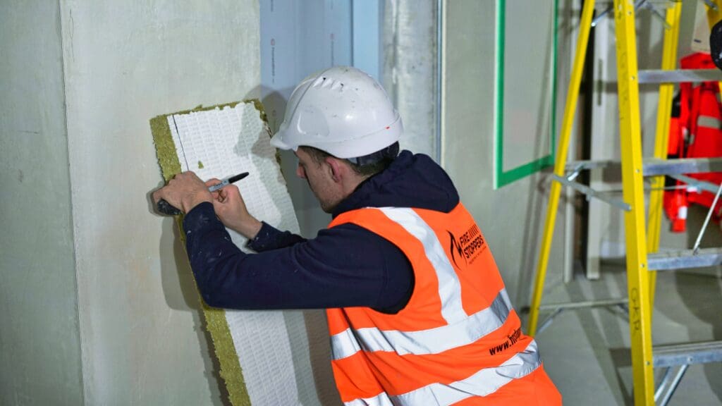 Image of an enginner in high visibility jacket installing a passive fire protection system