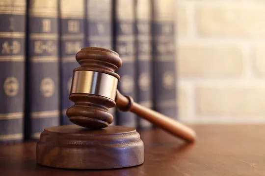 Image of a gavel on a desk with several leathbound books behind it stacked horizontally